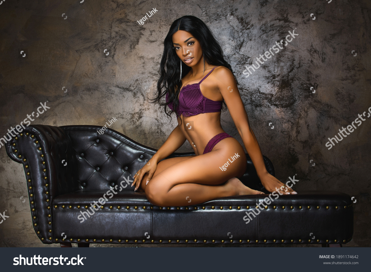 stock photo sexy young woman with long legs sitting on a dark brown leather 1891174642